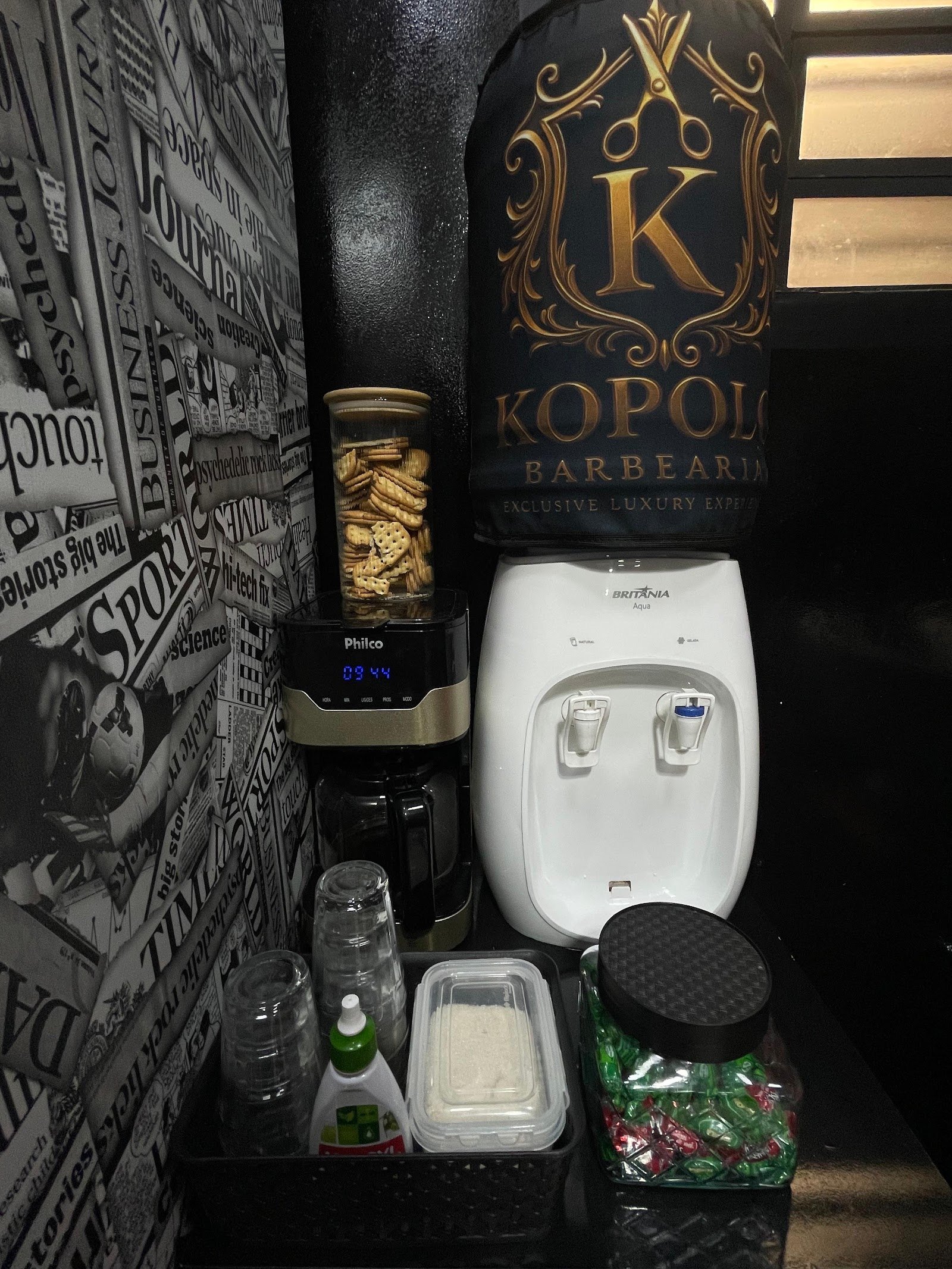 Canto de cortesia da Kopolo com água, café e balas, com capa da marca no bebedouro